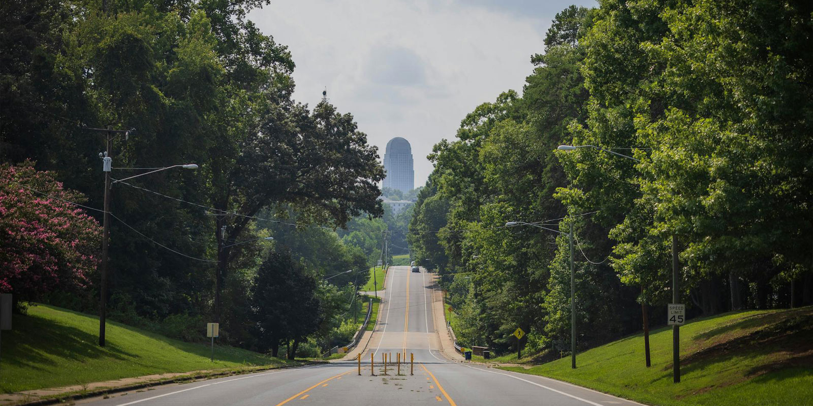 A photo of a tree-lined road heading into Winston-Salem, North Carolina, home of the criminal law defense team at the Allman Spry Law Firm.